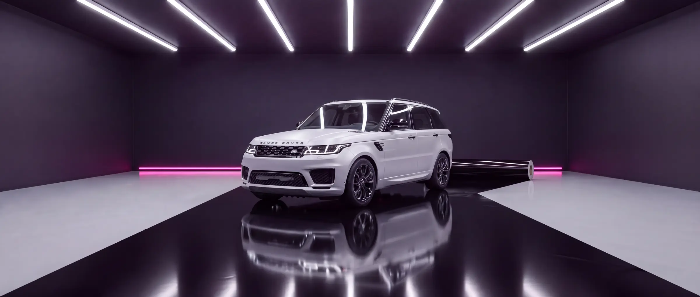 The same Range Rover Sport with all its chrome trim wrapped in gloss black, on a runway of gloss black film in a wrapping bay