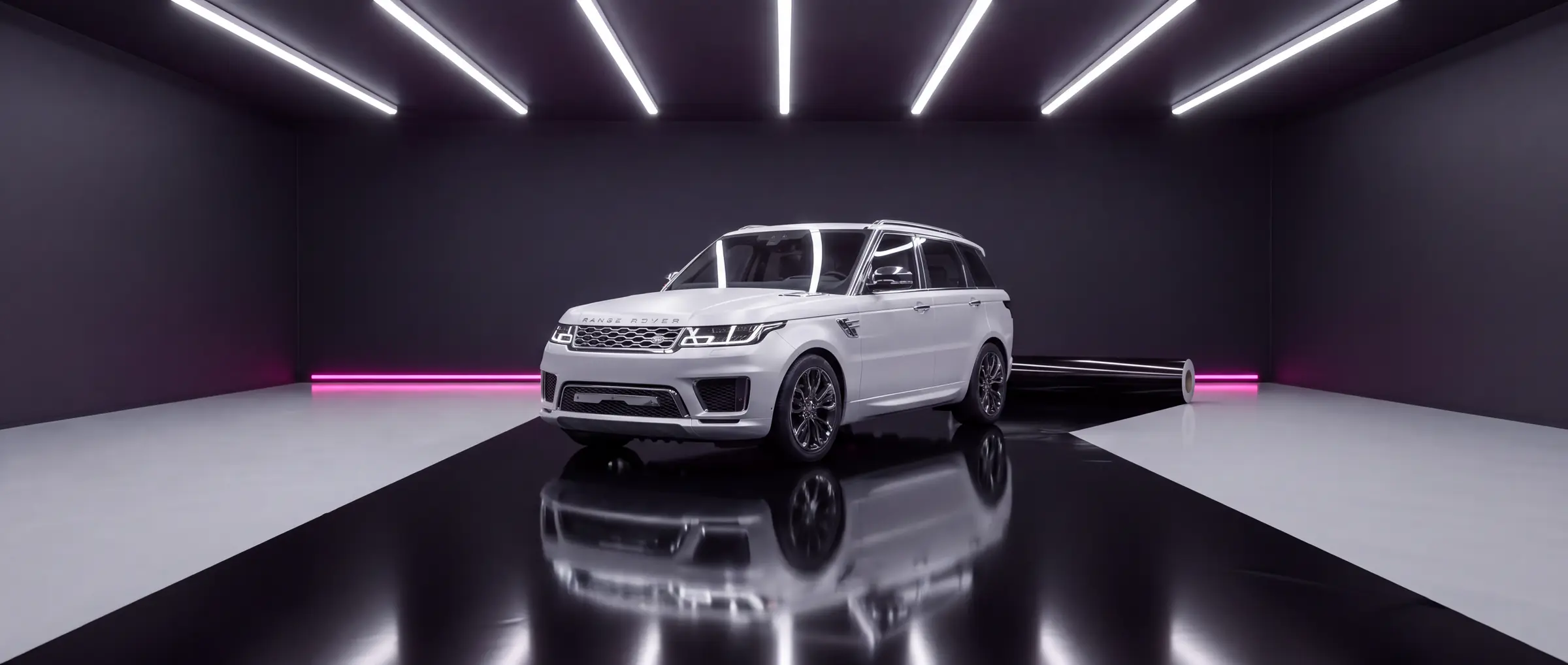 Range Rover Sport in satin white with its factory chrome trim, on a runway of gloss black film in a wrapping bay